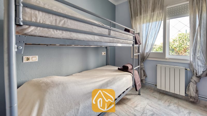 Holiday villas Costa Brava Spain - Villa Yara - Bedroom with grey metal bunk beds, white bedding, and a window with sheer curtains in Villa Yara