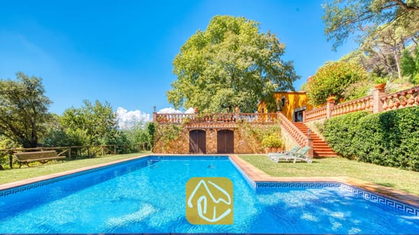 Vakantievilla's Costa Brava Spanje - Villa Paradise - Privézwembad bij Villa Paradise met helderblauw water, omringd door een groen grasveld, een stenen keermuur en comfortabele ligstoelen.
