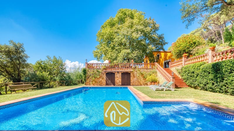 Vakantievilla's Costa Brava Spanje - Villa Paradise - Privézwembad bij Villa Paradise met helderblauw water, omringd door een groen grasveld, een stenen keermuur en comfortabele ligstoelen.