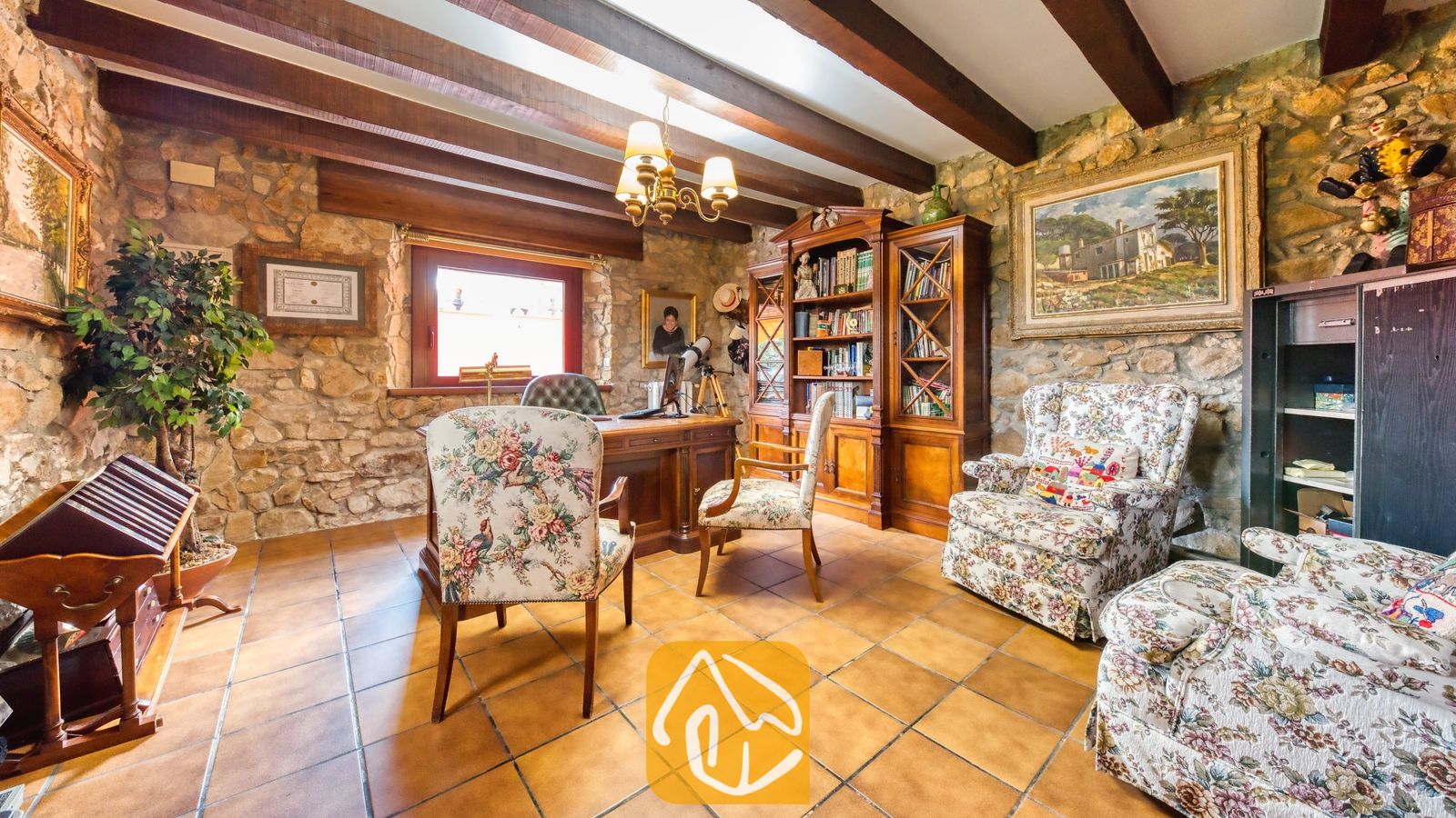 Vakantievilla's Costa Brava Spanje - Villa Paradise - Studeerkamer in Villa Paradise met authentieke stenen muren, houten plafondbalken, terracotta plavuizen en een grote houten boekenkast.