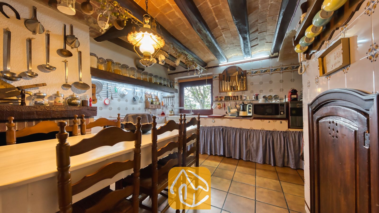 Vakantievilla's Costa Brava Spanje - Villa Paradise - Rustieke keuken met zichtbare houten balken, betegelde muren en een houten eettafel met stoelen in Villa Paradise