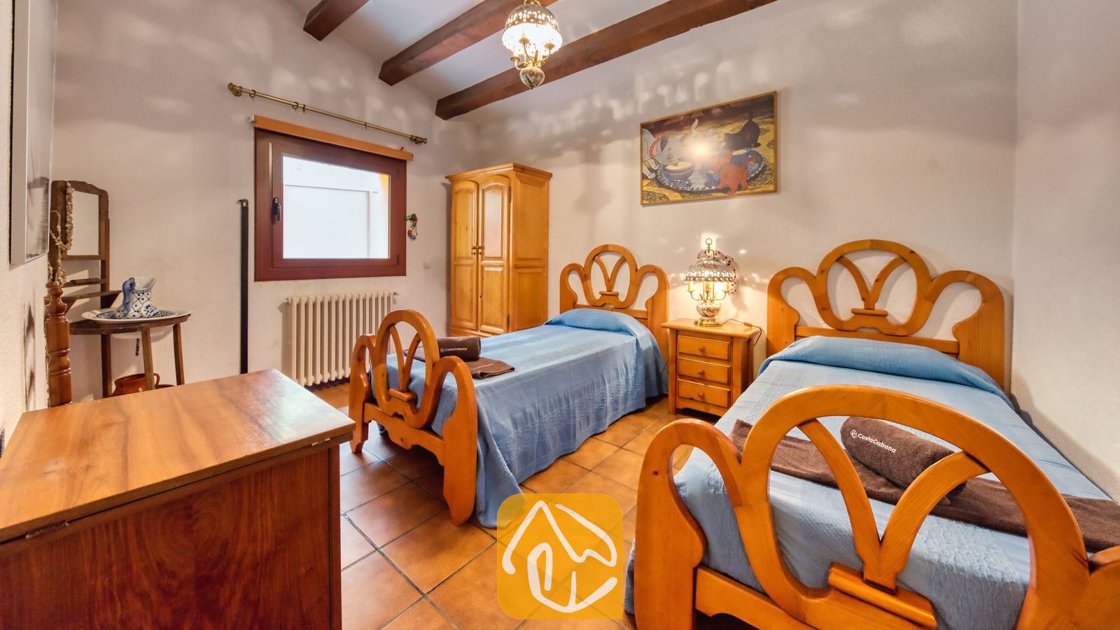 Vakantievilla's Costa Brava Spanje - Villa Paradise - Slaapkamer voorzien van twee houten eenpersoonsbedden met blauwe sprei, tegelvloer, authentieke houten balkenplafonds en een kleine kledingkast in Villa Paradise
