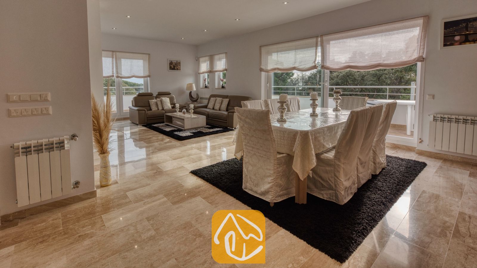 Vakantievilla's Costa Brava Spanje - Villa Madison - Ruime woon- en eetkamer in Villa Madison, voorzien van gepolijste marmeren vloeren, een overdekte eettafel en bruine leren banken.
