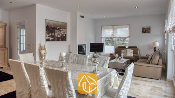 Vakantievilla's Costa Brava Spanje - Villa Madison - Woon- en eetkamer in Villa Madison, voorzien van een grote eettafel met een witte hoes, zilveren kandelaars en lichte, ﴾taan﴿ lederen banken.