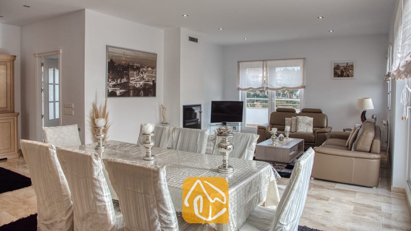 Vakantievilla's Costa Brava Spanje - Villa Madison - Woon- en eetkamer in Villa Madison, voorzien van een grote eettafel met een witte hoes, zilveren kandelaars en lichte, ﴾taan﴿ lederen banken.