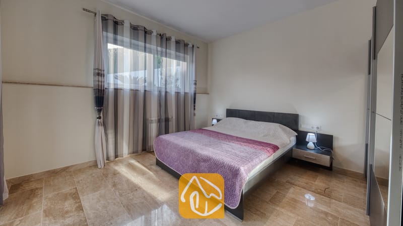 Holiday villas Costa Brava Spain - Villa Madison - Bedroom featuring a double bed with purple patterned cover, sheer striped curtains over the window, and polished marble tile flooring.