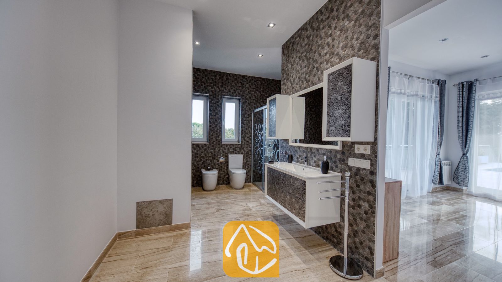 Vakantievilla's Costa Brava Spanje - Villa Madison - Moderne badkamer met donkere honingraatmozaïektegels, een zwevend wit badkamermeubel met gedessineerde kastdeuren en gepolijste marmeren vloeren.