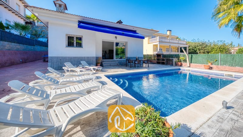 Vakantievilla's Costa Brava Spanje - Villa Zarita - Privézwembad met witte ligstoelen langs het plaveisel van het terras van Villa Zarita onder een helderblauwe hemel.