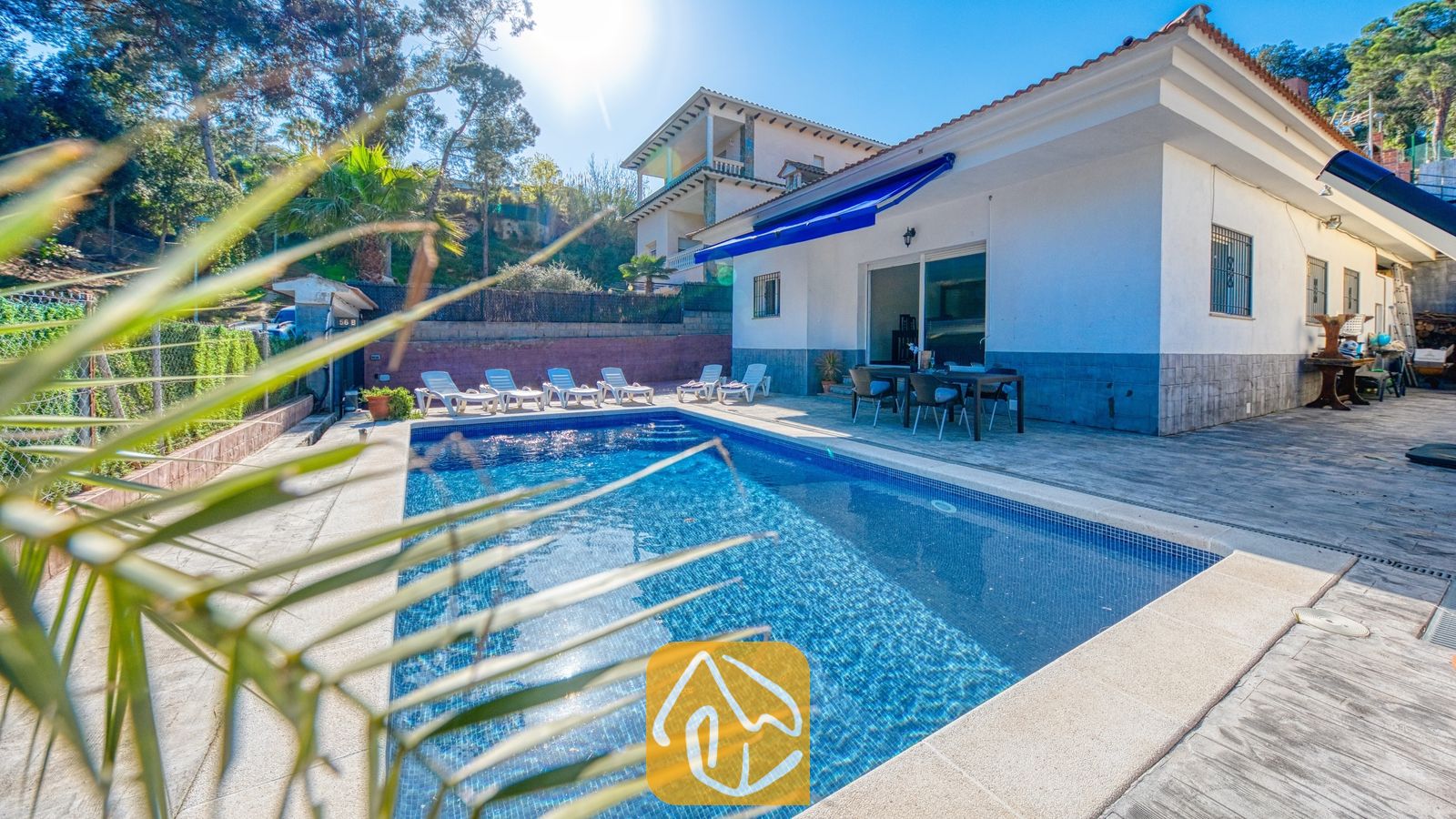 Vakantievilla's Costa Brava Spanje - Villa Zarita - Privézwembad en terras bij Villa Zarita, voorzien van blauw getegeld water, witte ligstoelen en een eethoek buiten onder een blauwe zonwering.