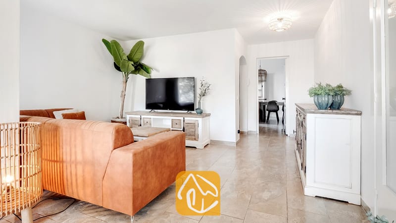 Vakantievilla's Costa Brava Spanje - Villa Tropicana - Woonkamer van Villa Tropicana met een bruine leren bank, flatscreen-televisie op een rustiek wit tv-meubel en tegelvloeren.