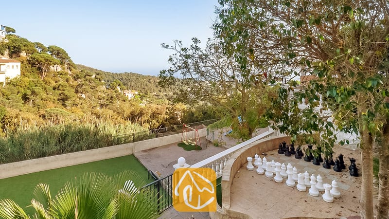 Vakantievilla's Costa Brava Spanje - Villa Tropicana - Groot buiten-schaakspel op een stenen terras bij Villa Tropicana met uitzicht op groene heuvels en bomen