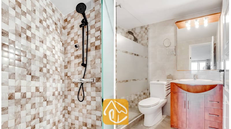 Vakantievilla's Costa Brava Spanje - Villa Tropicana - Moderne badkamer met een inloopdouche met zwarte kranen en beslag, neutrale mozaïektegels, een wit toilet en een houten badkamermeubel met een geïntegreerde wastafel en spiegel.