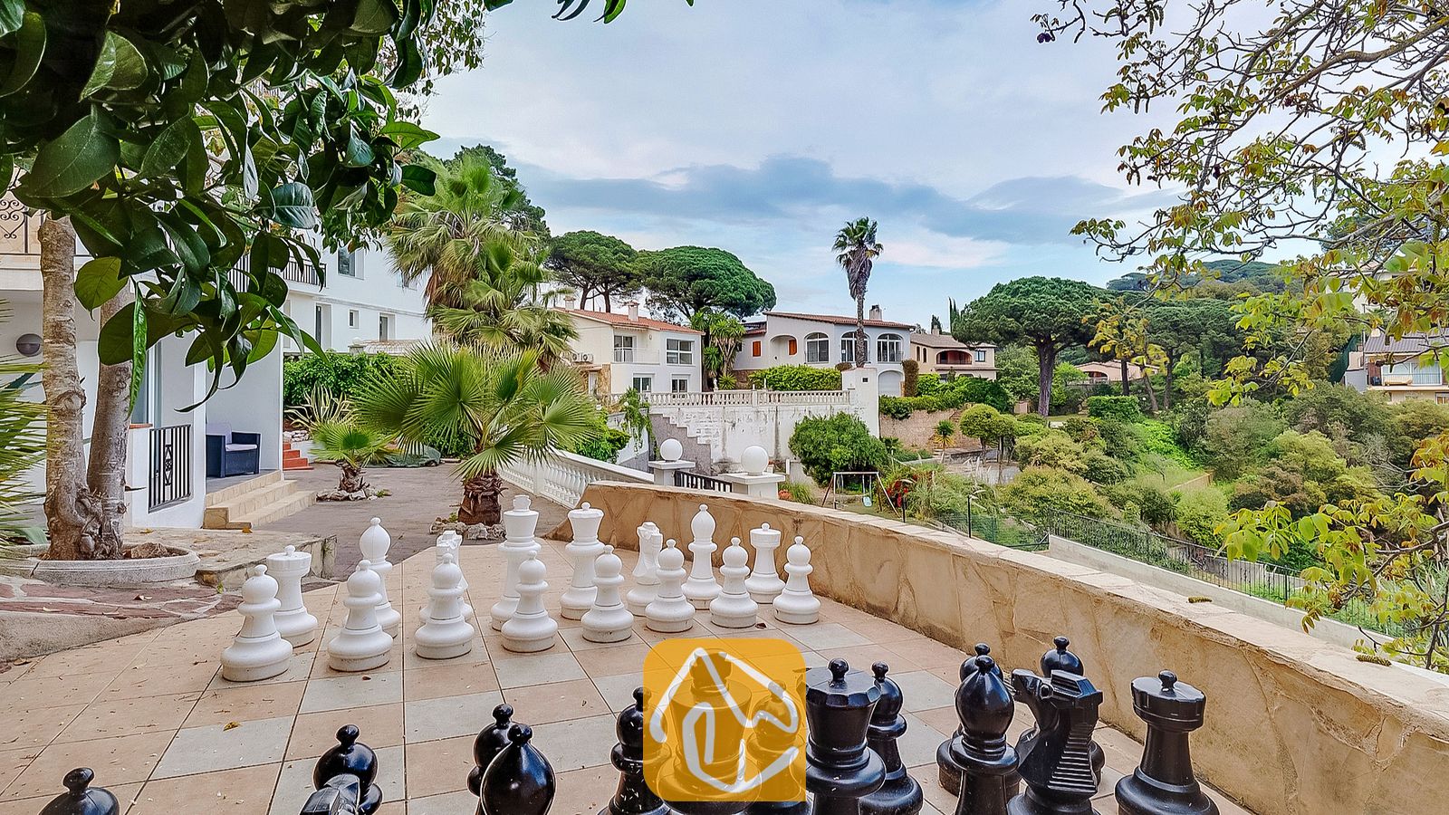 Vakantievilla's Costa Brava Spanje - Villa Tropicana - Een levensgroot schaakspel op een betegeld terras bij Villa Tropicana, met uitzicht op de omliggende Spaanse heuvels en bomen.