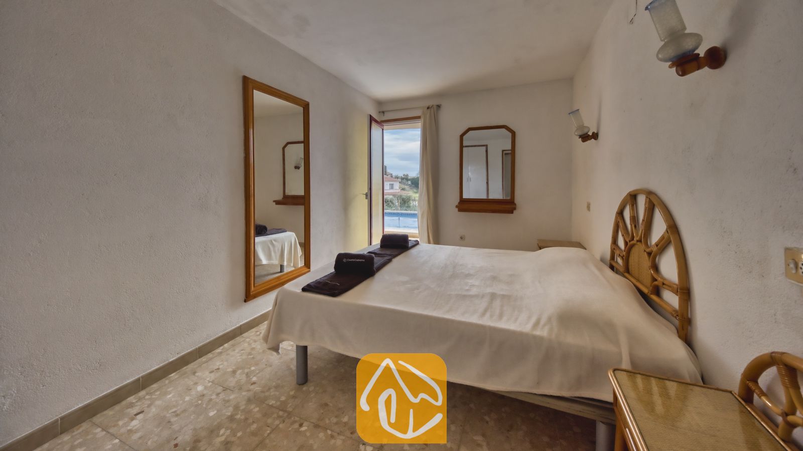 Vakantievilla's Costa Brava Spanje - Villa Janet - Slaapkamer met een tweepersoonsbed voorzien van een houten hoofdbord, tegelvloeren en een open doorgang die uitzicht biedt op een buitenzwembad.