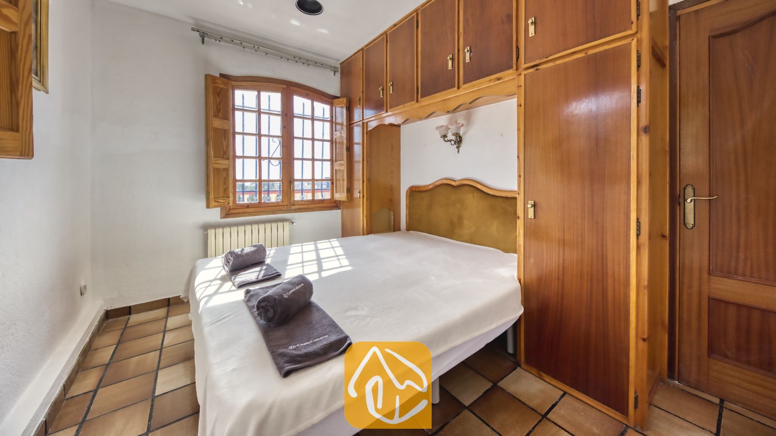 Vakantievilla's Costa Brava Spanje - Villa Janet - Slaapkamer in Villa Janet met een tweepersoonsbed, ingebouwde houten kasten en een raam met houten luiken dat uitkijkt op natuurlijke lichtinval.