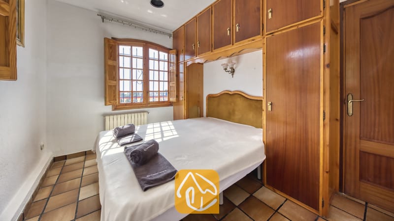 Vakantievilla's Costa Brava Spanje - Villa Janet - Slaapkamer in Villa Janet met een tweepersoonsbed, ingebouwde houten kasten en een raam met houten luiken dat uitkijkt op natuurlijke lichtinval.