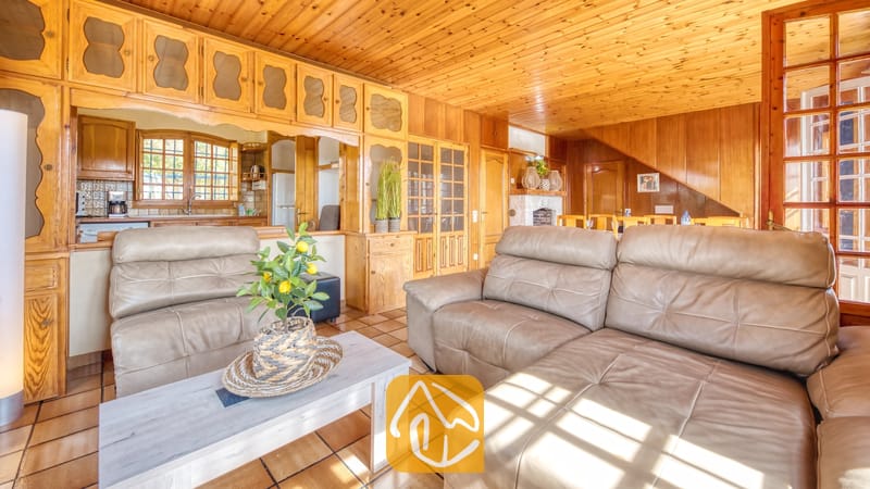 Vakantievilla's Costa Brava Spanje - Villa Janet - Interieur van de woonkamer in Villa Janet met houten wanden en plafonds, bruine leren banken en een witte salontafel met een klein potje met een citroenboompje.