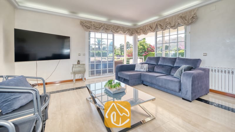 Vakantievilla's Costa Brava Spanje - Villa Beyonce - Woonkamer van Villa Beyonce met een grote blauwe hoekbank, een glazen salontafel met potplanten en een wandtelevisie.