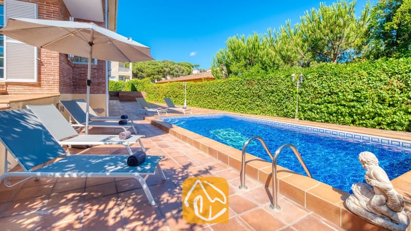 Vakantievilla's Costa Brava Spanje - Villa Beyonce - Privé-buitenzwembad bij Villa Beyonce met helderblauw water, metalen handgrepen en een stenen standbeeld naast een rij grijze ligstoelen op een betegeld terras.
