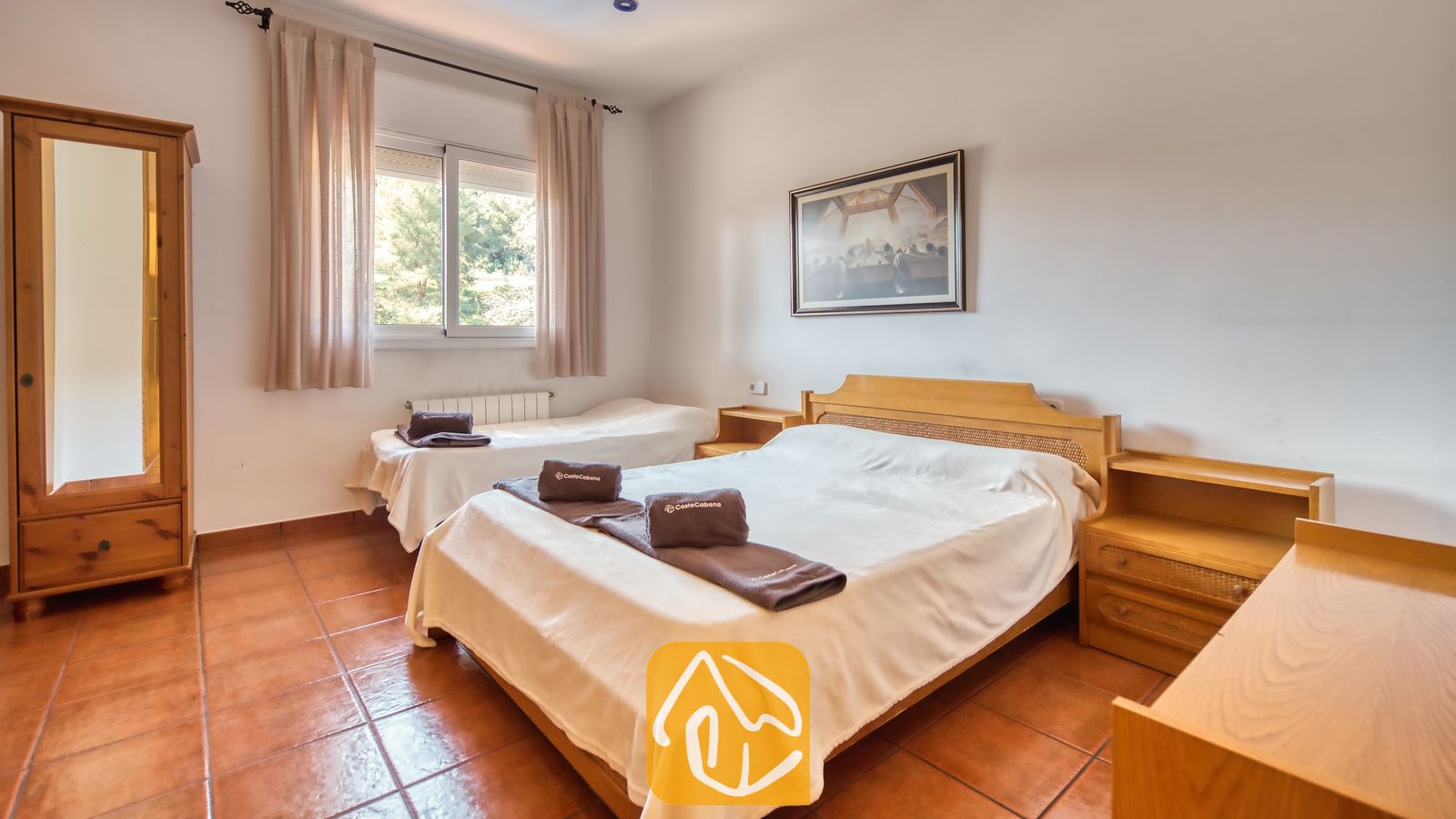 Vakantievilla's Costa Brava Spanje - Villa Valeria - Slaapkamer met een tweepersoonsbed, een eenpersoonsbed, houten meubels, tegelvloeren en een raam met gordijnen bij Villa Valeria.