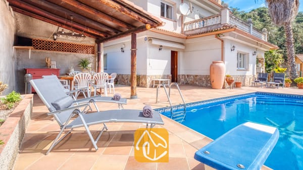 Vakantievilla's Costa Brava Spanje - Villa Valeria - Privézwembad met grijze ligstoelen en een betegeld terras bij Villa Valeria in Spanje, voorzien van een overdekt buiten dinerterras en een witte buitenzijde van de villa.