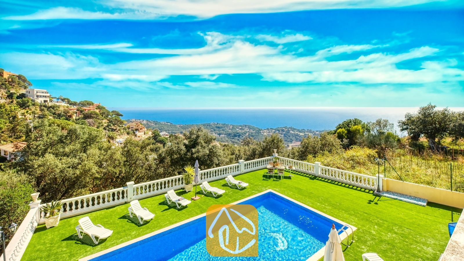 Vakantievilla's Costa Brava Spanje - Villa Sunrise - Privézwembad en een groen gazon bij Villa Sunrise, voorzien van witte ligstoelen en een terras met een witte balustrade en uitzicht op zee en de heuvels onder een blauwe hemel.