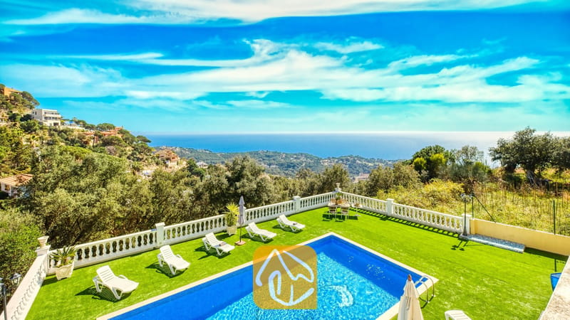 Vakantievilla's Costa Brava Spanje - Villa Sunrise - Privézwembad en een groen gazon bij Villa Sunrise, voorzien van witte ligstoelen en een terras met een witte balustrade en uitzicht op zee en de heuvels onder een blauwe hemel.