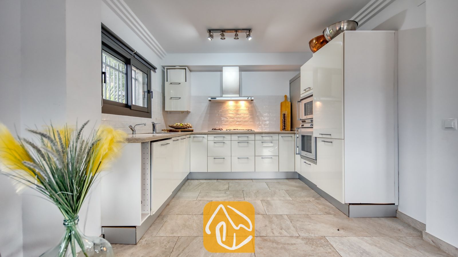 Vakantievilla's Costa Brava Spanje - Villa Palmera - Moderne keuken met hoogglans witte kasten, een betegelde achterwand en ingebouwde roestvrijstalen ovens in Villa Palmera