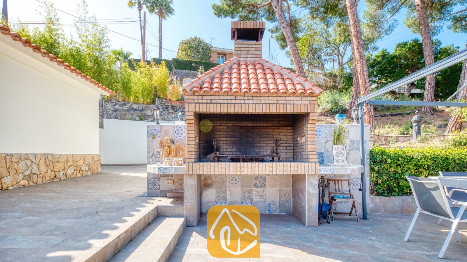 Vakantievilla's Costa Brava Spanje - Villa Palmera - Stenen barbecue met betegelde basis en dakpannen van terracotta, gelegen op een buitenterras bij Villa Palmera.
