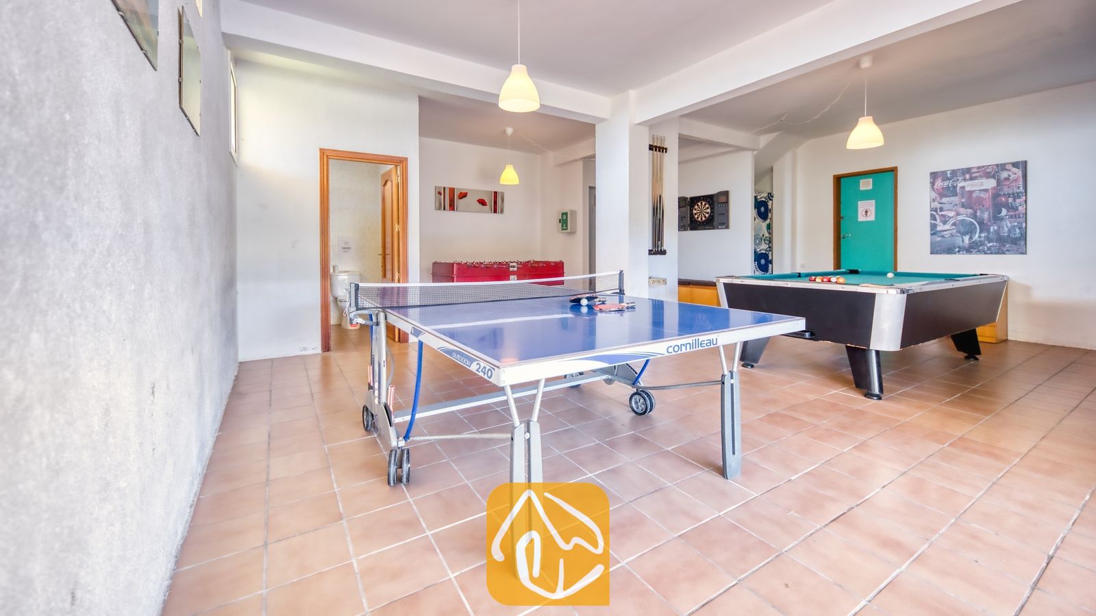 Vakantievilla's Costa Brava Spanje - Villa Holiday - Spelkamer met een blauwe tennistafel op de voorgrond, een groene biljarttafel aan de rechterkant en een rode tafelvoetbaltafel op de achtergrond.