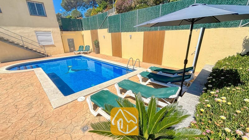 Vakantievilla's Costa Brava Spanje - Villa Holiday - Privé buitenzwembad bij Villa Holiday, omringd door groene ligbedden, een donkere parasol en een stenen terras.