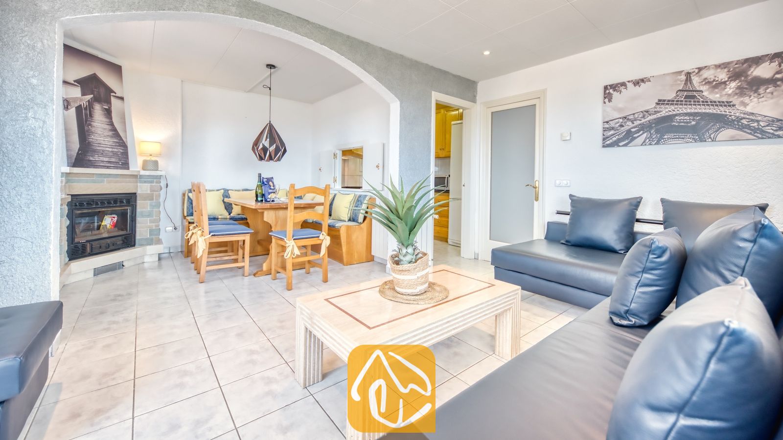 Vakantievilla's Costa Brava Spanje - Villa Maribel - Woon- en eethoek in Villa Maribel met donkerblauwe leren banken, een tegelhaard en een houten eettafel met ingebouwde hoekbank.