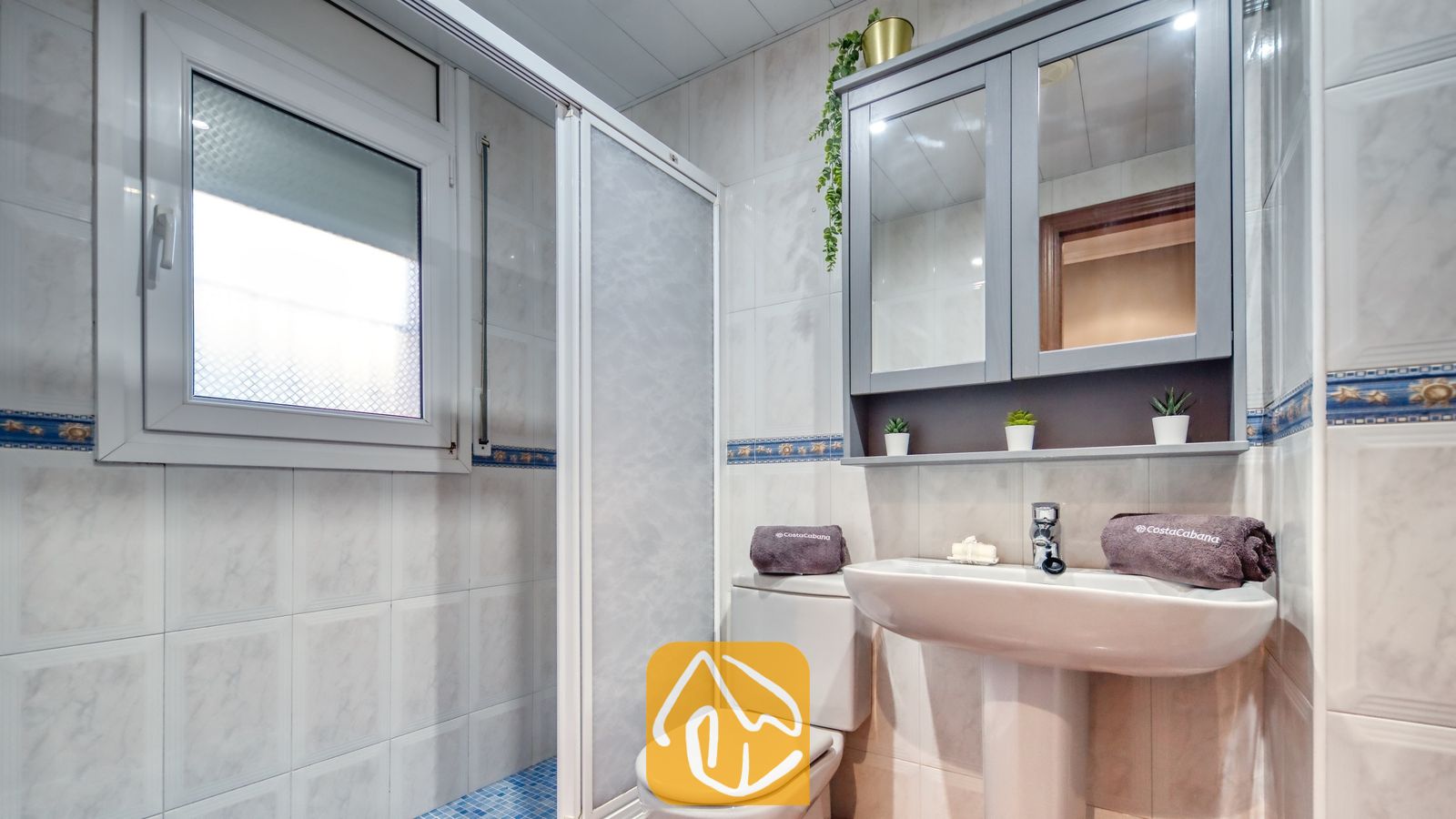 Vakantievilla's Costa Brava Spanje - Villa Summertime - Badkamer met een vrijstaande wastafel, een wit toilet en een grijze spiegelkast tegen betegelde muren