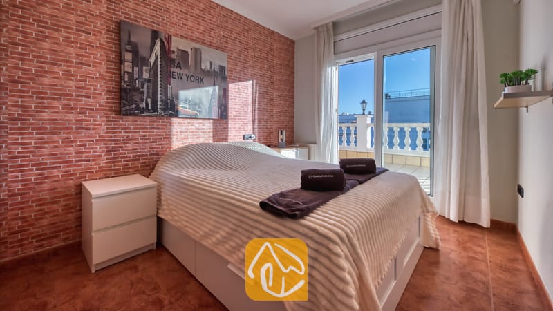 Vakantievilla's Costa Brava Spanje - Villa Summertime - Slaapkamer met een tweepersoonsbed, een karakteristieke muur van rode baksteen, muurdecoratie van de skyline van New York en schuifpui die toegang biedt tot een balkon.