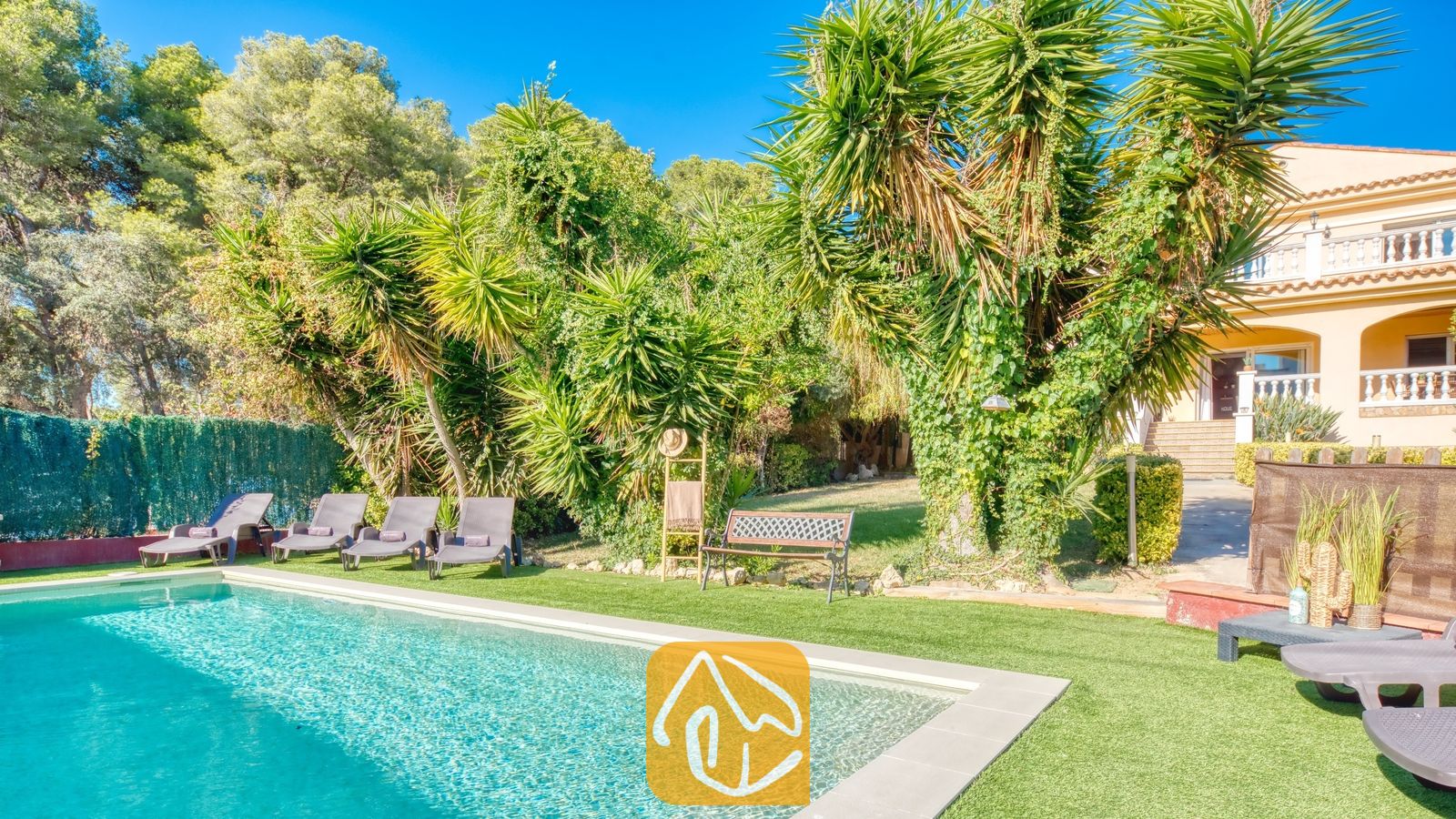 Vakantievilla's Costa Brava Spanje - Villa Summertime - Privézwembad met ligstoelen op kunstgras bij Villa Summertime, omringd door palmbomen en weelderig groen