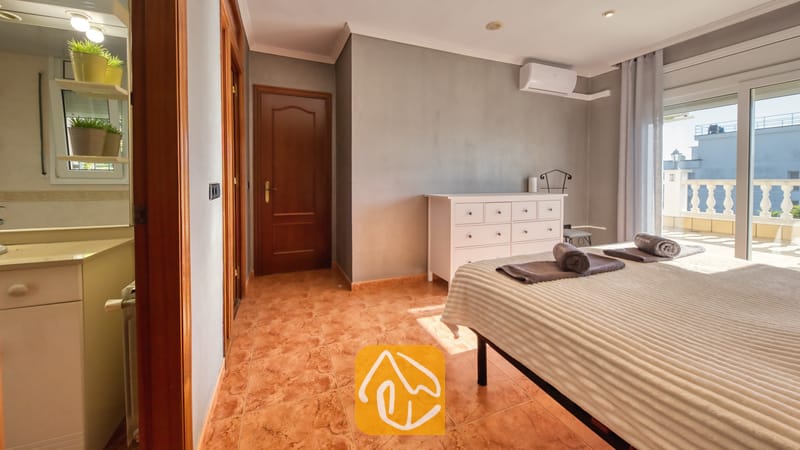 Vakantievilla's Costa Brava Spanje - Villa Summertime - Slaapkamer met grijze muren, tegelvloeren, een witte commode en glazen schuifpui die toegang biedt tot een lichte balkon.