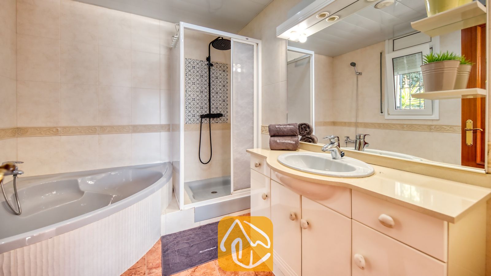 Vakantievilla's Costa Brava Spanje - Villa Summertime - Badkamer voorzien van een hoekbad, een glazen inloopdouche met zwarte kranen en een wastafelmeubel met een grote spiegel.