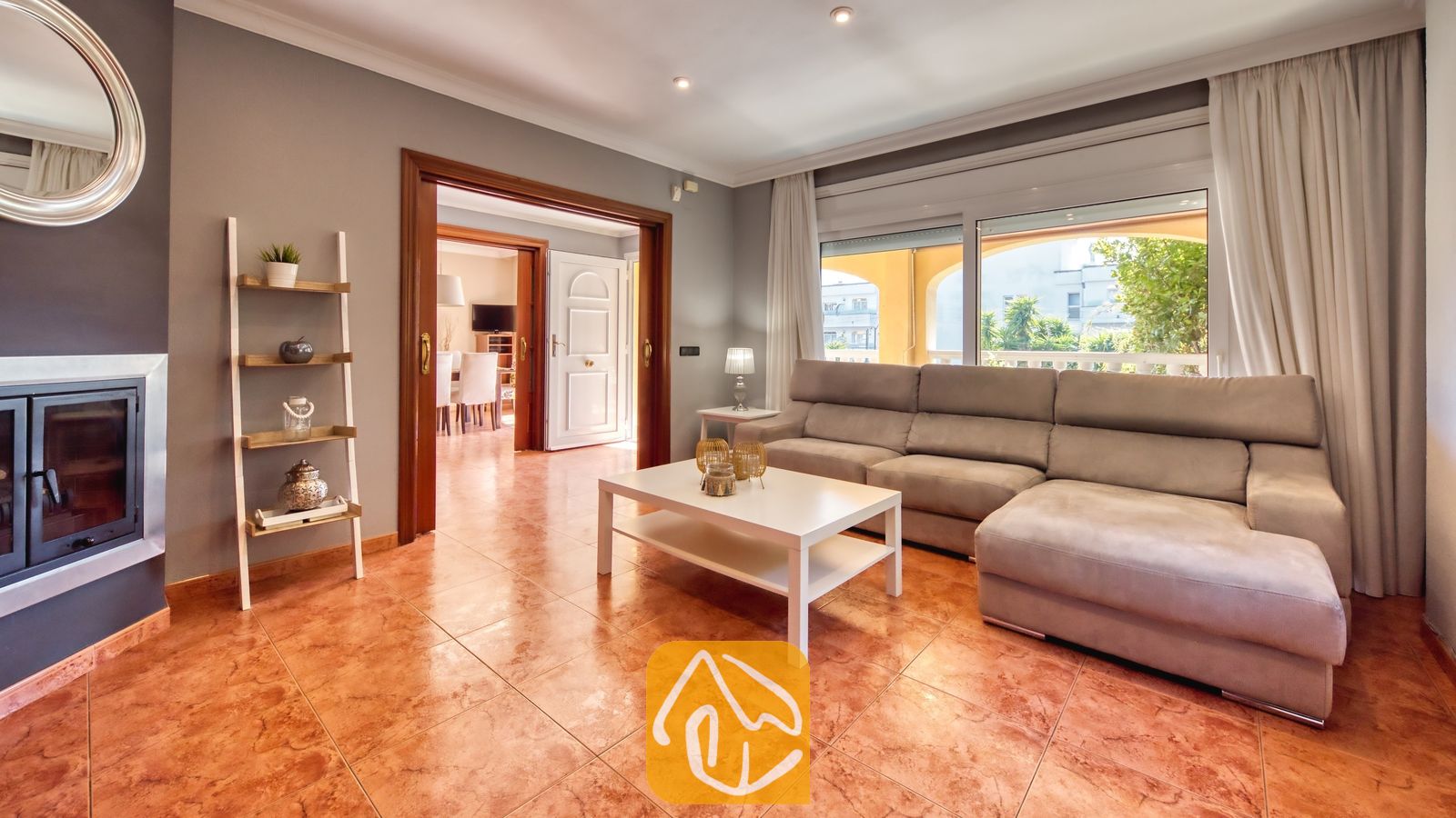 Vakantievilla's Costa Brava Spanje - Villa Summertime - Woonkamer met een grote grijze hoekbank, een witte salontafel en een tegelvloer, en een deuropening die leidt naar een aangrenzende kamer in Villa Summertime.