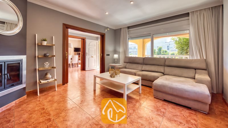 Vakantievilla's Costa Brava Spanje - Villa Summertime - Woonkamer met een grote grijze hoekbank, een witte salontafel en een tegelvloer, en een deuropening die leidt naar een aangrenzende kamer in Villa Summertime.