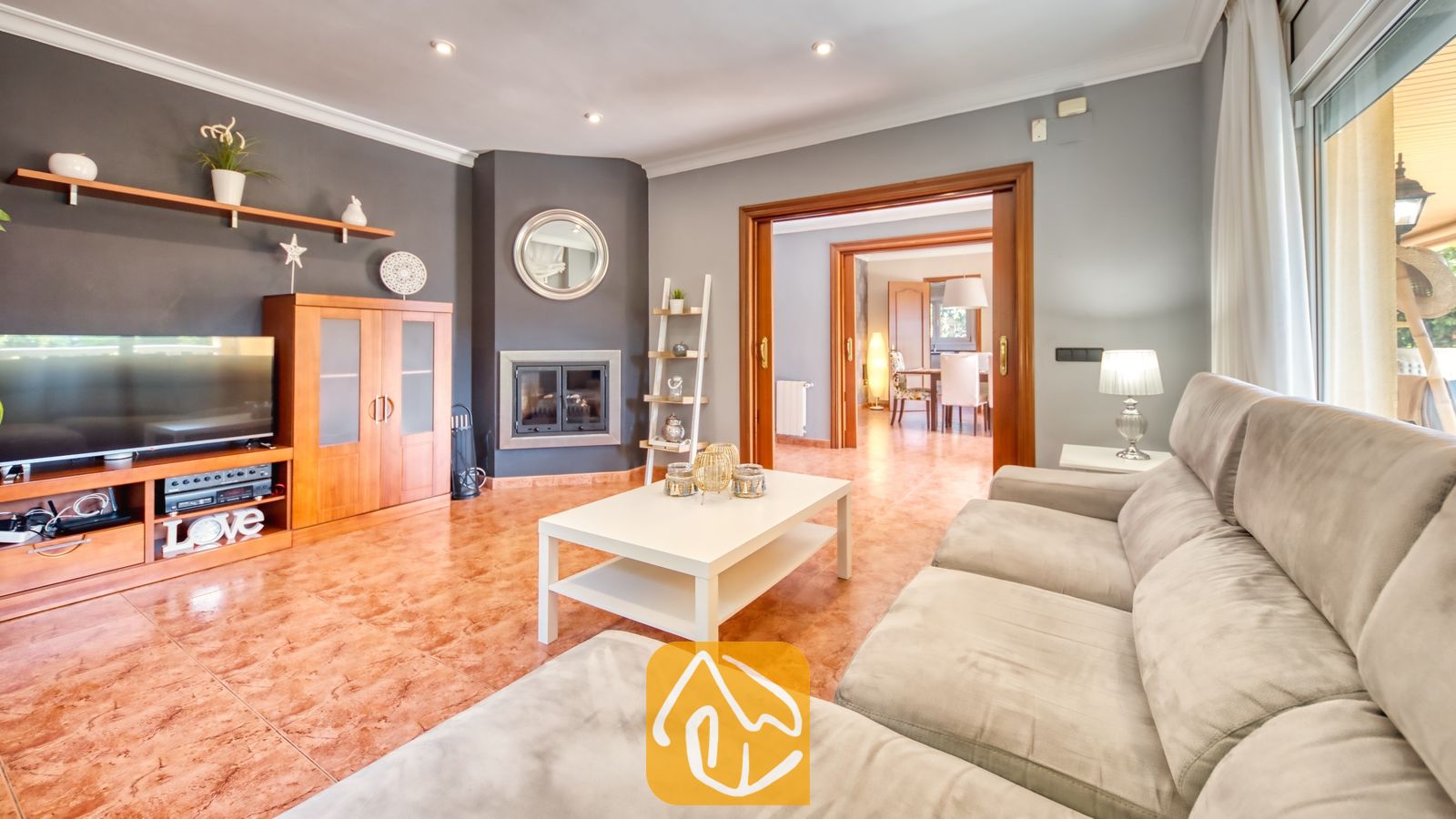 Vakantievilla's Costa Brava Spanje - Villa Summertime - Woonkamer van Villa Summertime met een grijze bank, een witte salontafel en een houten tv-meubel onder een aan de muur gemaakte televisie.