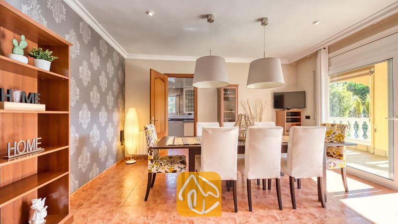 Vakantievilla's Costa Brava Spanje - Villa Summertime - Eetkamer met een donkerhouten tafel, witte gestoffeerde stoelen, stoelen met een motief aan het hoofdeneinde en twee grote hanglampen bij Villa Summertime.