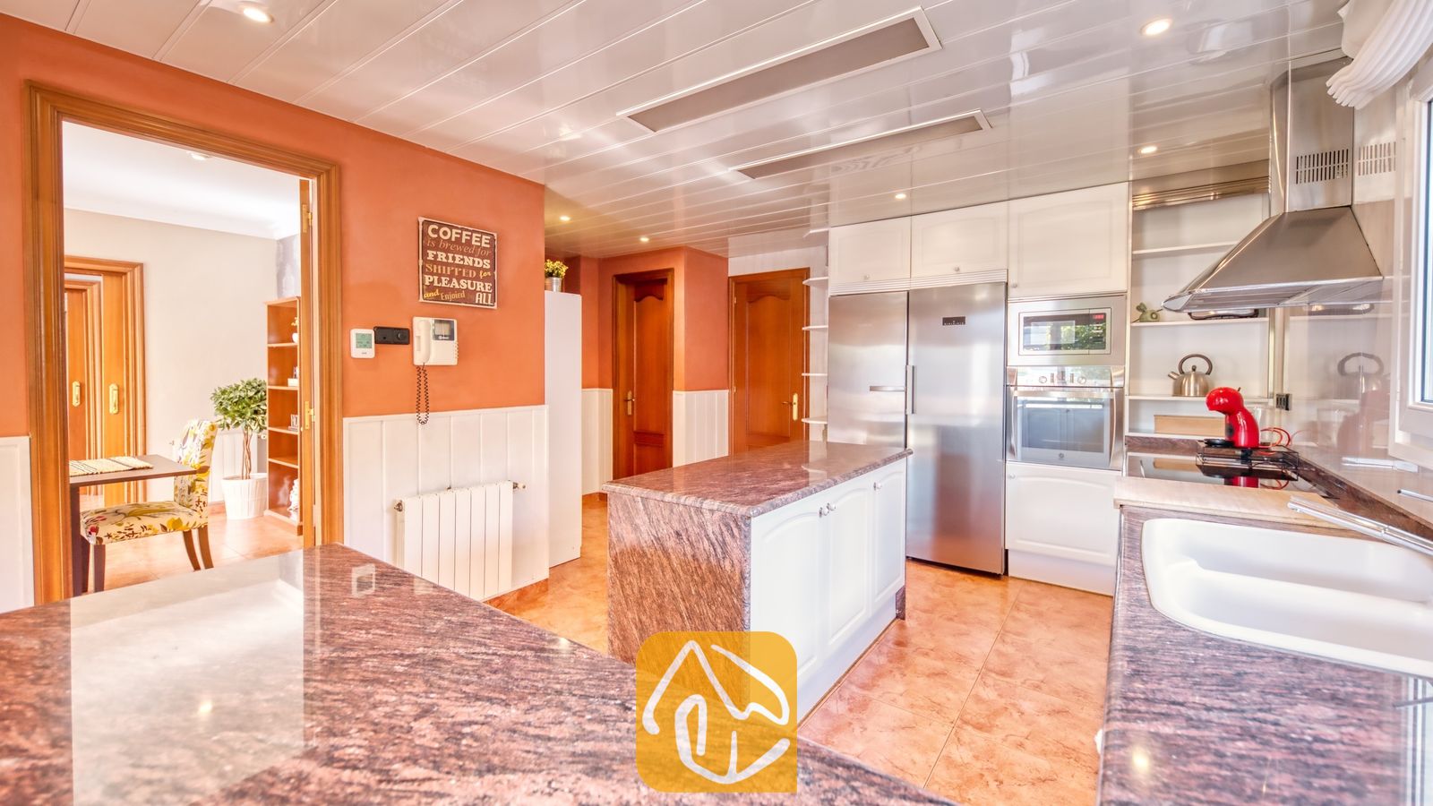 Vakantievilla's Costa Brava Spanje - Villa Summertime - Ruime keuken voorzien van granieten aanrechtbladen, roestvrijstalen apparatuur en opvallende oranje muren met witte lambrisering.