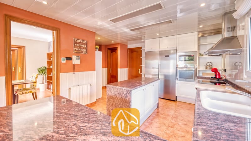 Vakantievilla's Costa Brava Spanje - Villa Summertime - Ruime keuken voorzien van granieten aanrechtbladen, roestvrijstalen apparatuur en opvallende oranje muren met witte lambrisering.