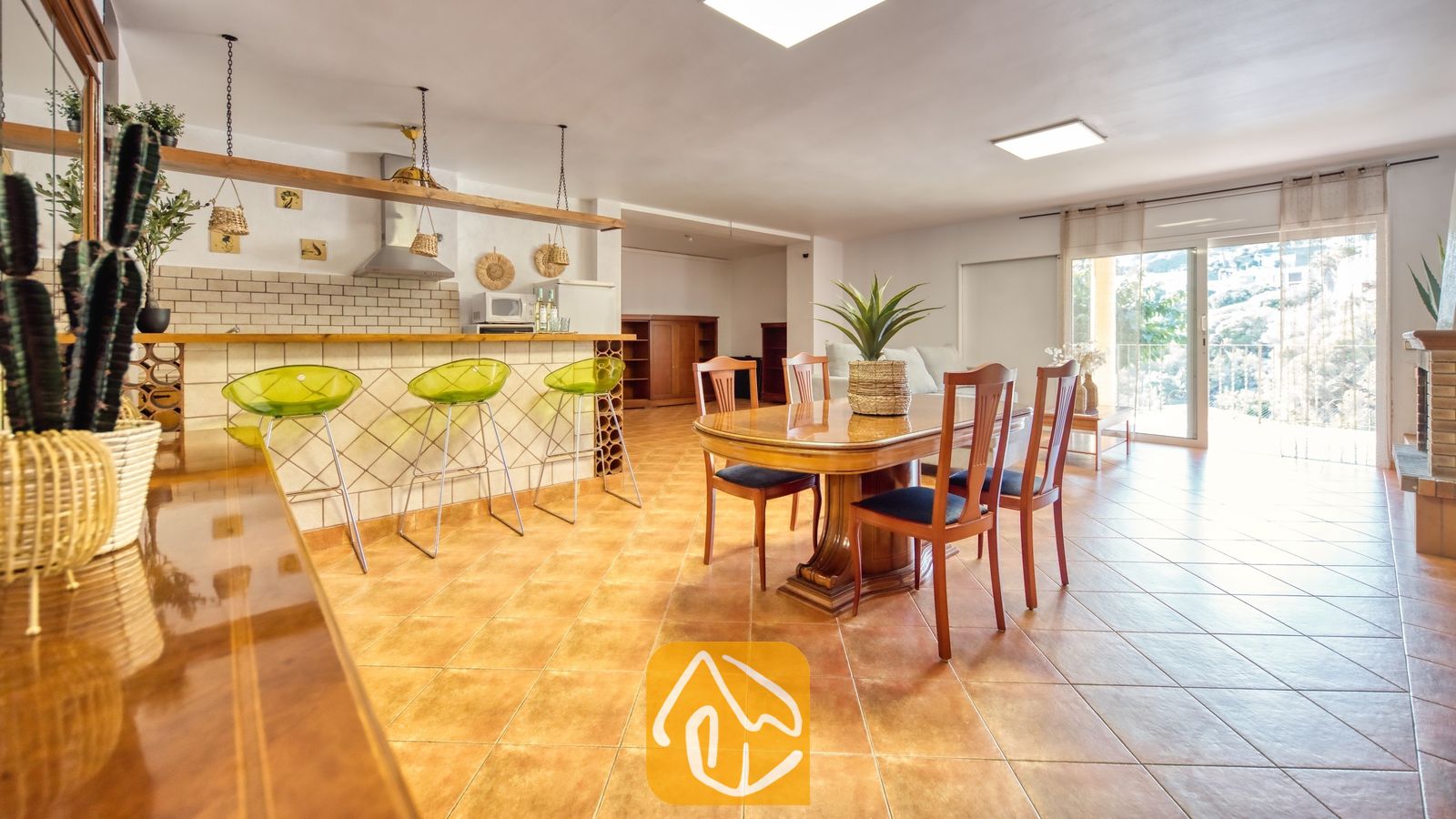 Vakantievilla's Costa Brava Spanje - Villa Marysol - De open eethoek en keuken van Villa Marysol zijn voorzien van een houten eettafel met zes stoelen, een tegelbar met limoengroene krukken en terracotta vloertegels.