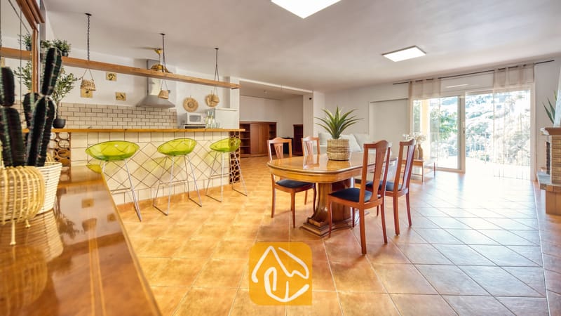Vakantievilla's Costa Brava Spanje - Villa Marysol - De open eethoek en keuken van Villa Marysol zijn voorzien van een houten eettafel met zes stoelen, een tegelbar met limoengroene krukken en terracotta vloertegels.
