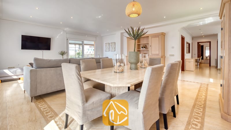 Vakantievilla's Costa Brava Spanje - Villa Marysol - Ruime woon- en eetkamer in Villa Marysol, voorzien van een beige stenen eettafel, gestoffeerde stoelen, een grijze bank en tegelvloeren.
