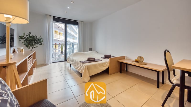 Vakantievilla's Costa Brava Spanje - Apartment Gaudi - Slaapkamer in Appartement Gaudi met een tweepersoonsbed, tegelvloeren en glazen schuifdeuren die toegang bieden tot een balkon.