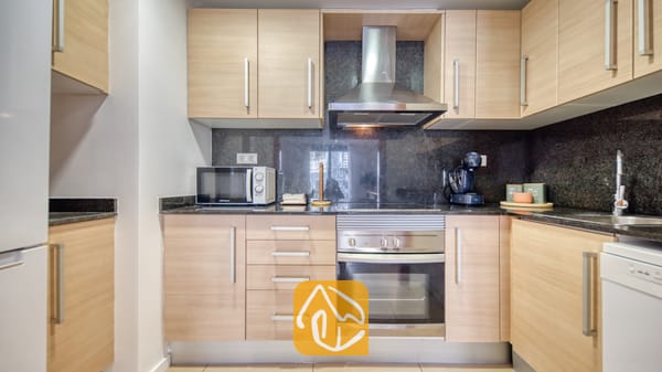 Vakantievilla's Costa Brava Spanje - Apartment Gaudi - Keuken met licht houten kasten, donkere granieten aanrechtbladen, een roestvrijstalen oven en een bijpassende afzuigkap