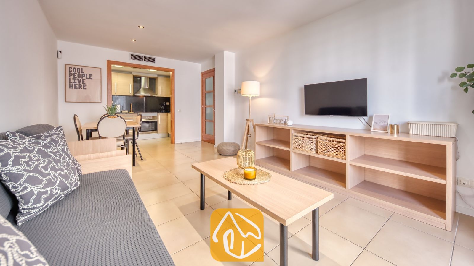 Vakantievilla's Costa Brava Spanje - Apartment Gaudi - Woonkamer met een grijze bank, houten salontafel en een aan de muur gemonteerde televisie in Apartment Gaudi