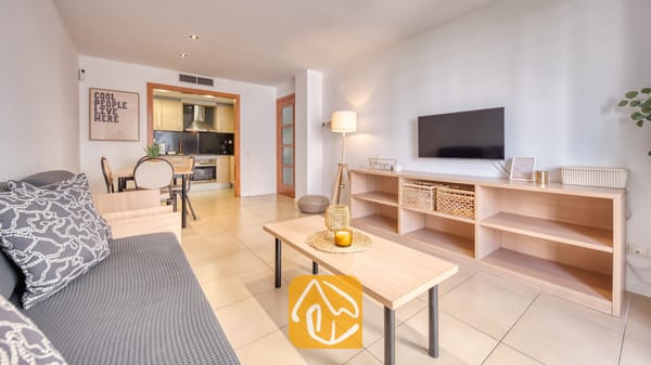 Vakantievilla's Costa Brava Spanje - Apartment Gaudi - Woonkamer met een grijze bank, houten salontafel en een aan de muur gemonteerde televisie in Apartment Gaudi